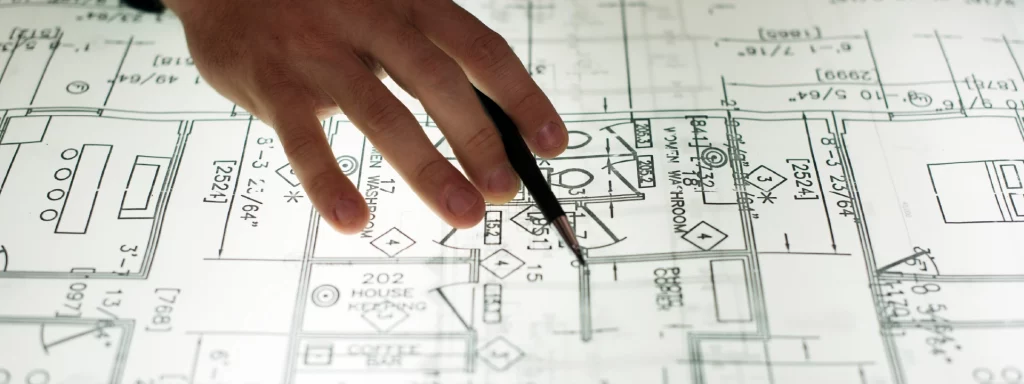 Symbolbild Bauplanung im Krankenhaus: Hand mit Stift auf Bauplan