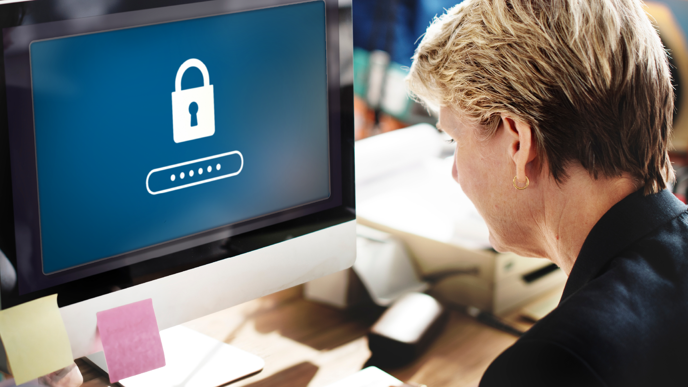 So schützen Sie Ihr Krankenhaus vor einem Cyberangriff Eine Frau sitzt vor einem Computerbildschirm, auf dem ein Schloss zu sehen ist.