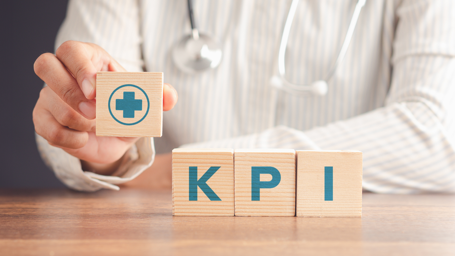 2408_Controlling.Kennzahlen-im-KH_Beitragsbild_quer_Leistungsseiten Symbolbild Kennzahlen im Krankenhaus: Bausteine mit den Buchstaben K, P und I - eine Hand hält einen Baustein mit einem Kreuz hoch